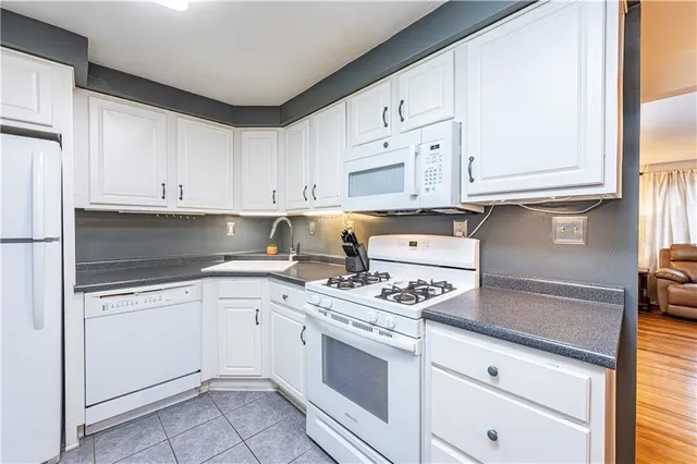 a kitchen with granite countertop white cabinets and white appliances