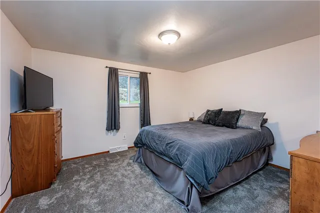 a spacious bedroom with a bed and a flat screen tv