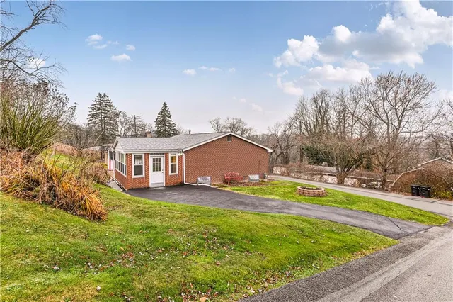 a view of a house with a big yard and large trees