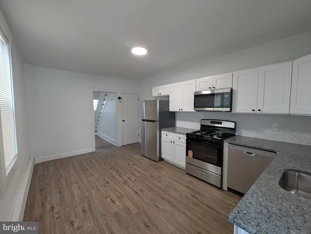 a kitchen with granite countertop a stove a sink and a refrigerator