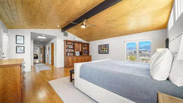 a spacious bedroom with a bed and dresser with wooden floor