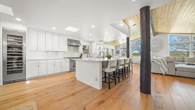 a kitchen with stainless steel appliances kitchen island wooden floors and white cabinets