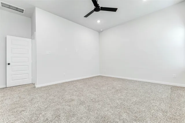 an empty room with a ceiling fan and carpet