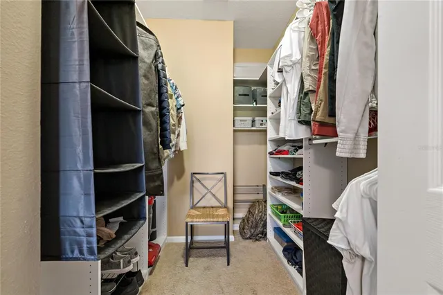 a view of walk in closet with clothes and shoes