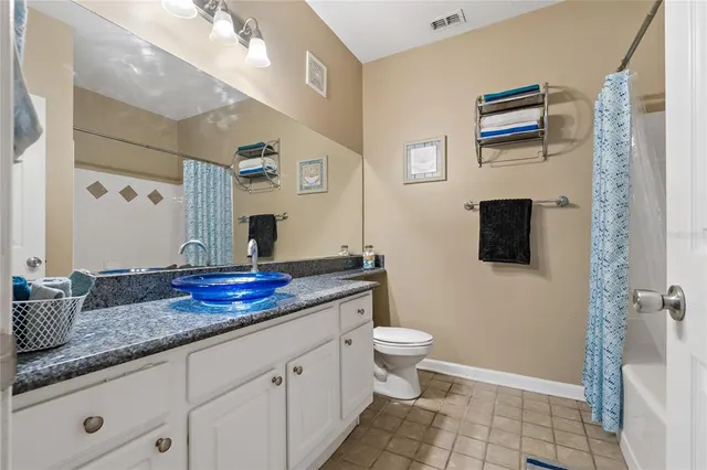 a spacious bathroom with a granite countertop sink a toilet a mirror and shower