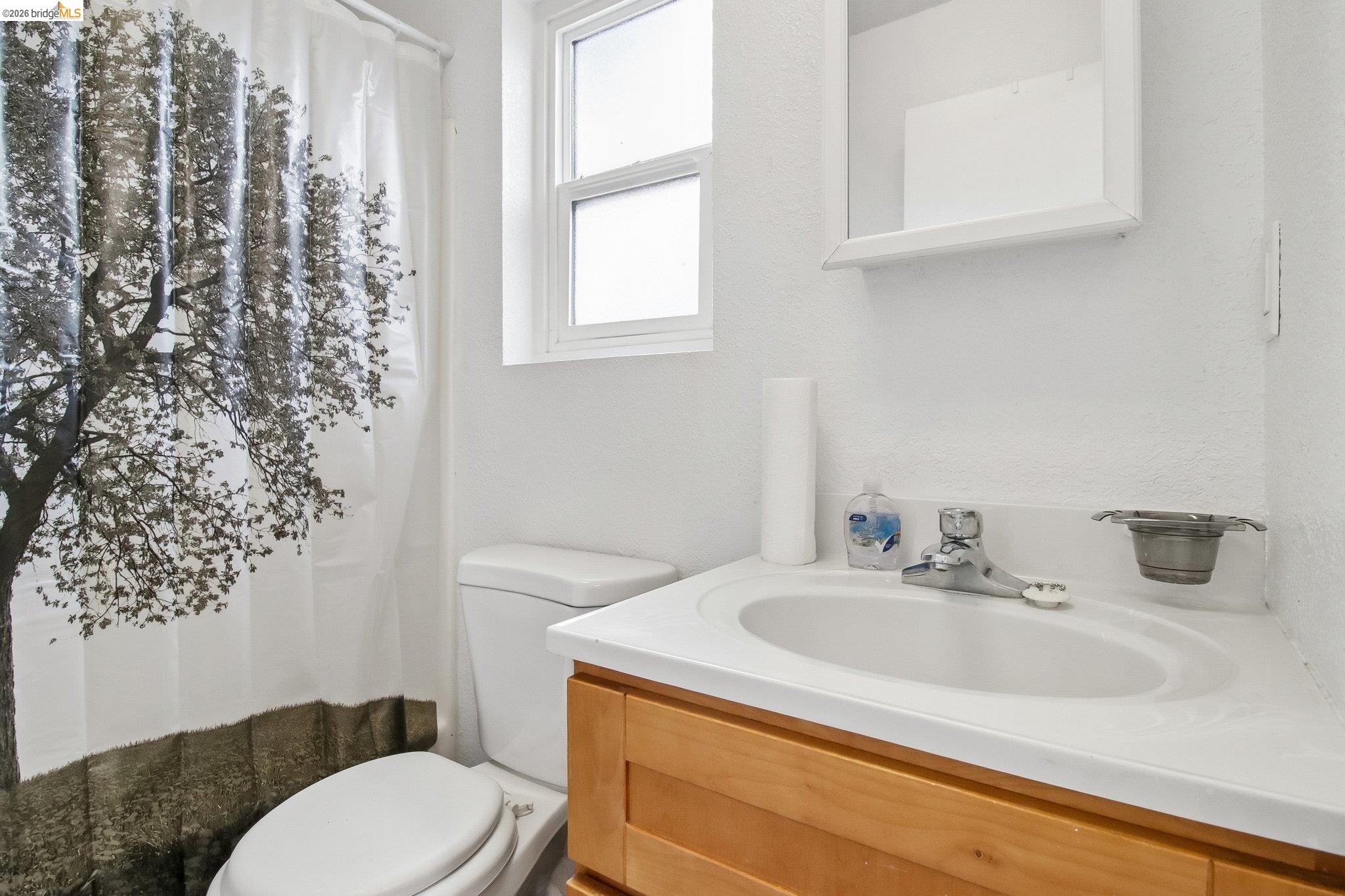 874 Pine Street Oakland, CA 94607 - Photo 18 of 39 Bathroom featuring a single-pane window, white vanity with integrated sink, wood-finish cabinetry, and a white medicine cabinet