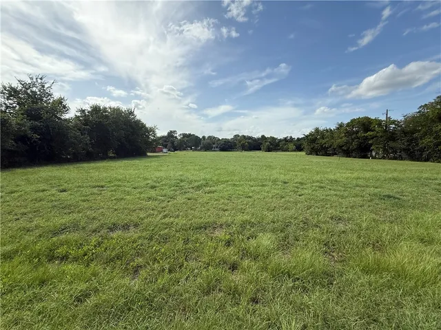 a view of a field with an trees in the background