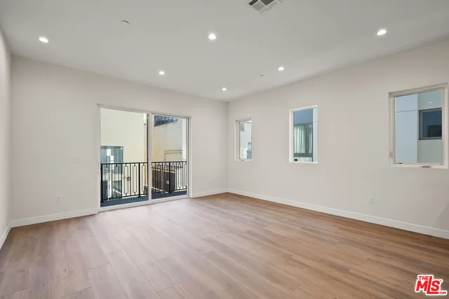 a view of an empty room with wooden floor and windows