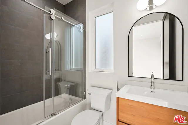 a bathroom with a granite countertop sink mirror toilet and bathtub