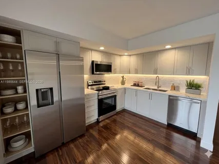 a kitchen with granite countertop a refrigerator and a stove top oven