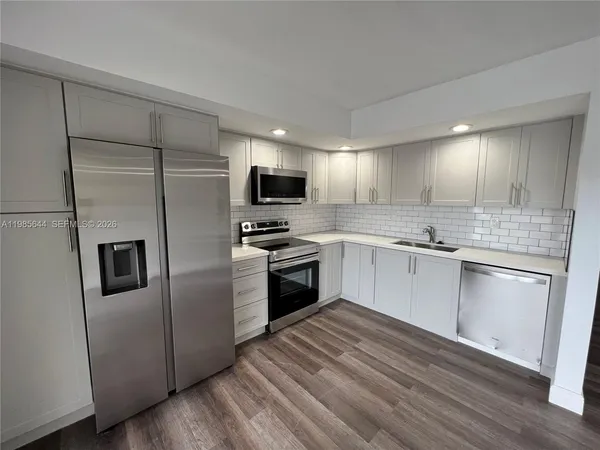 a kitchen with wooden floors and stainless steel appliances