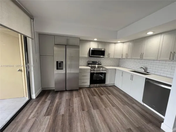 a kitchen with wooden floors and stainless steel appliances