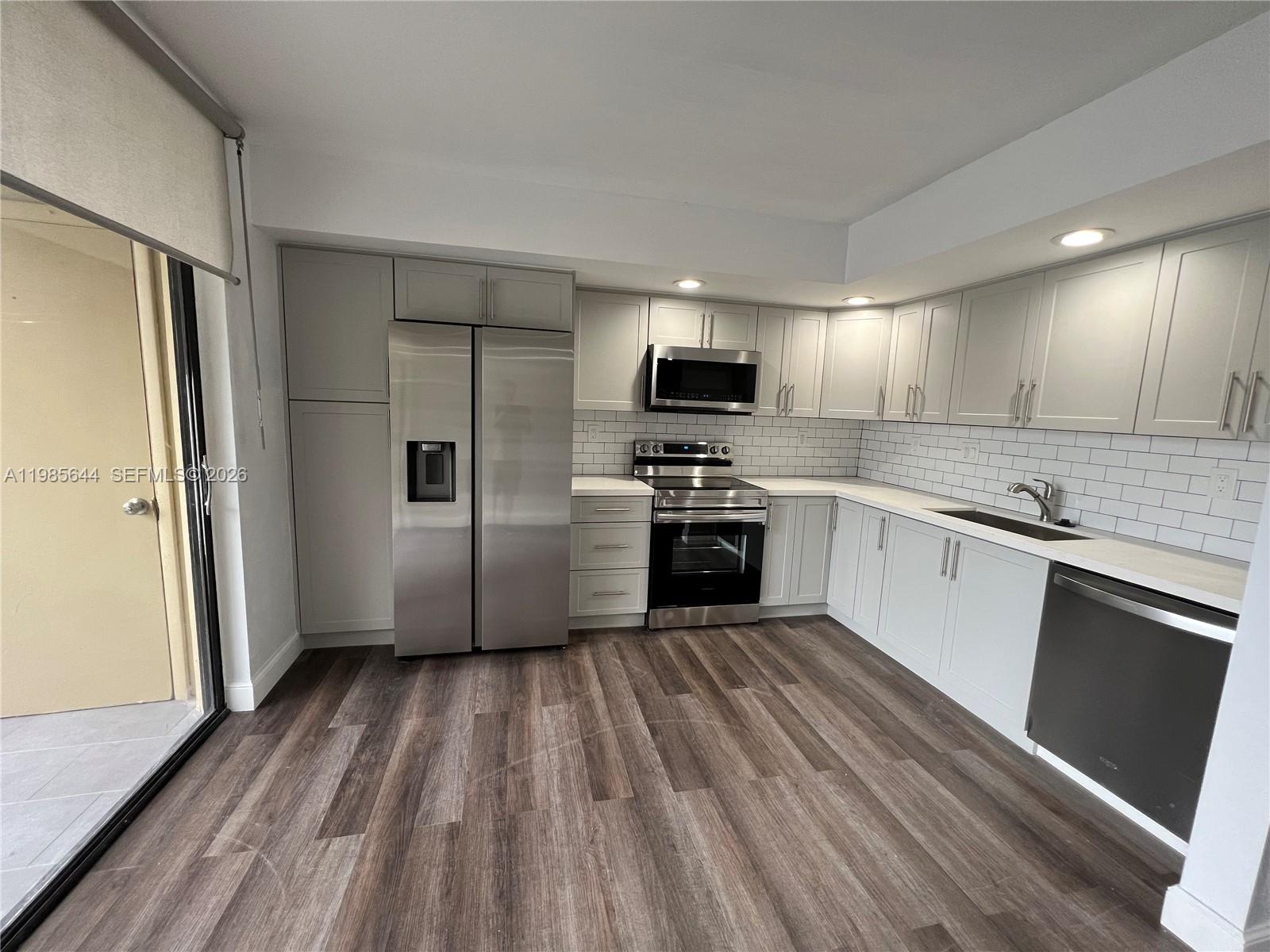 8635 Northwest 8th Street, Unit 211 Miami, FL 33126 - Photo 3 of 17 a kitchen with wooden floors and stainless steel appliances
