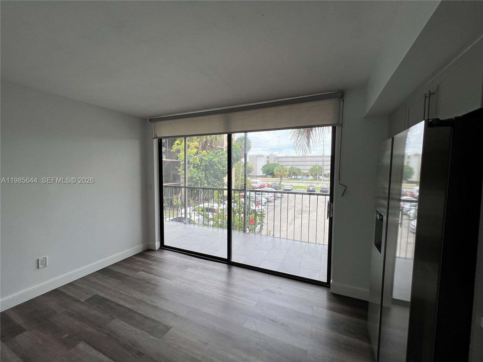 8635 Northwest 8th Street, Unit 211 Miami, FL 33126 - Photo 5 of 17 a view of an empty room with wooden floor and a window