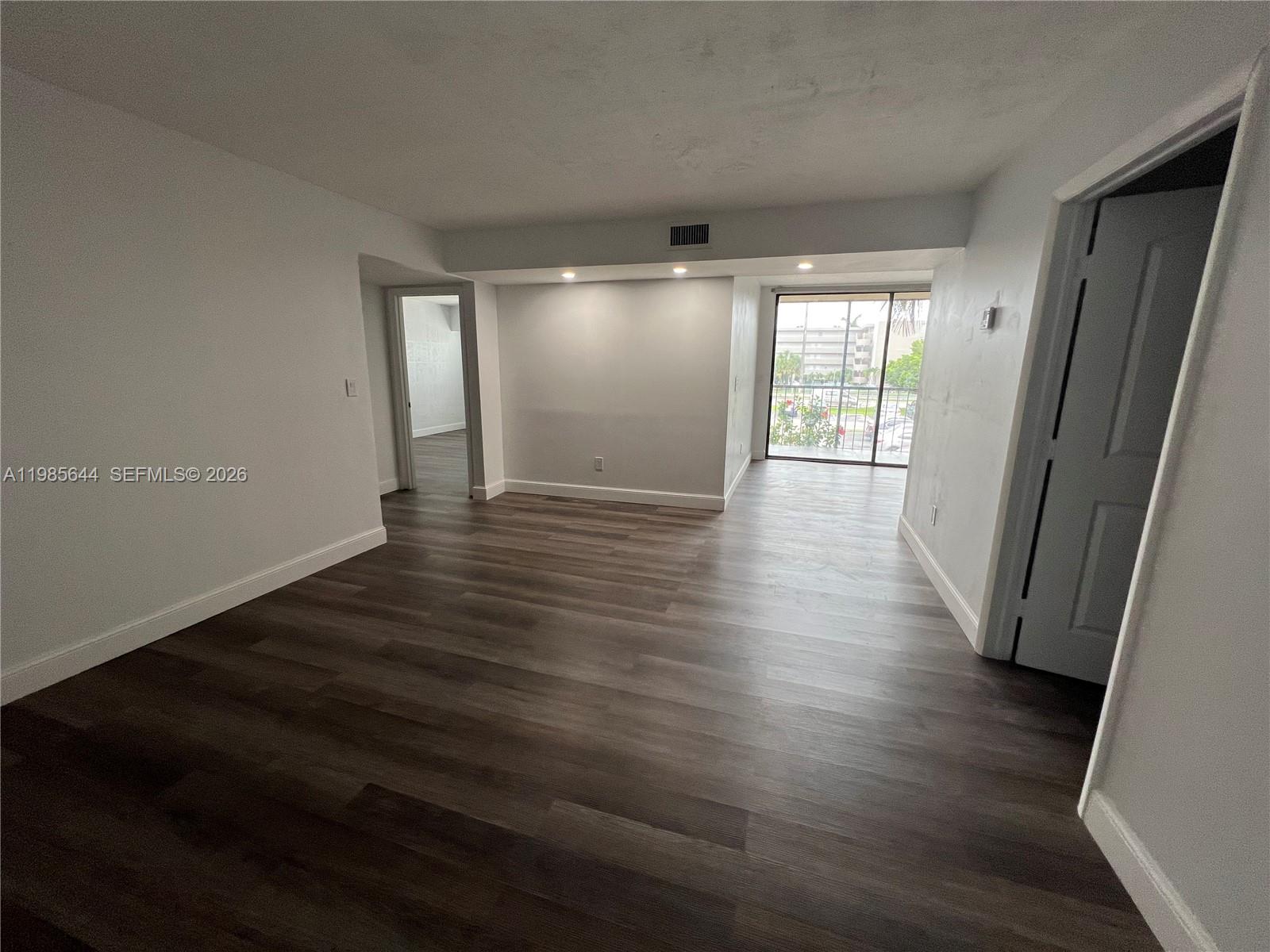 8635 Northwest 8th Street, Unit 211 Miami, FL 33126 - Photo 7 of 17 a view of an empty room with wooden floor and a window