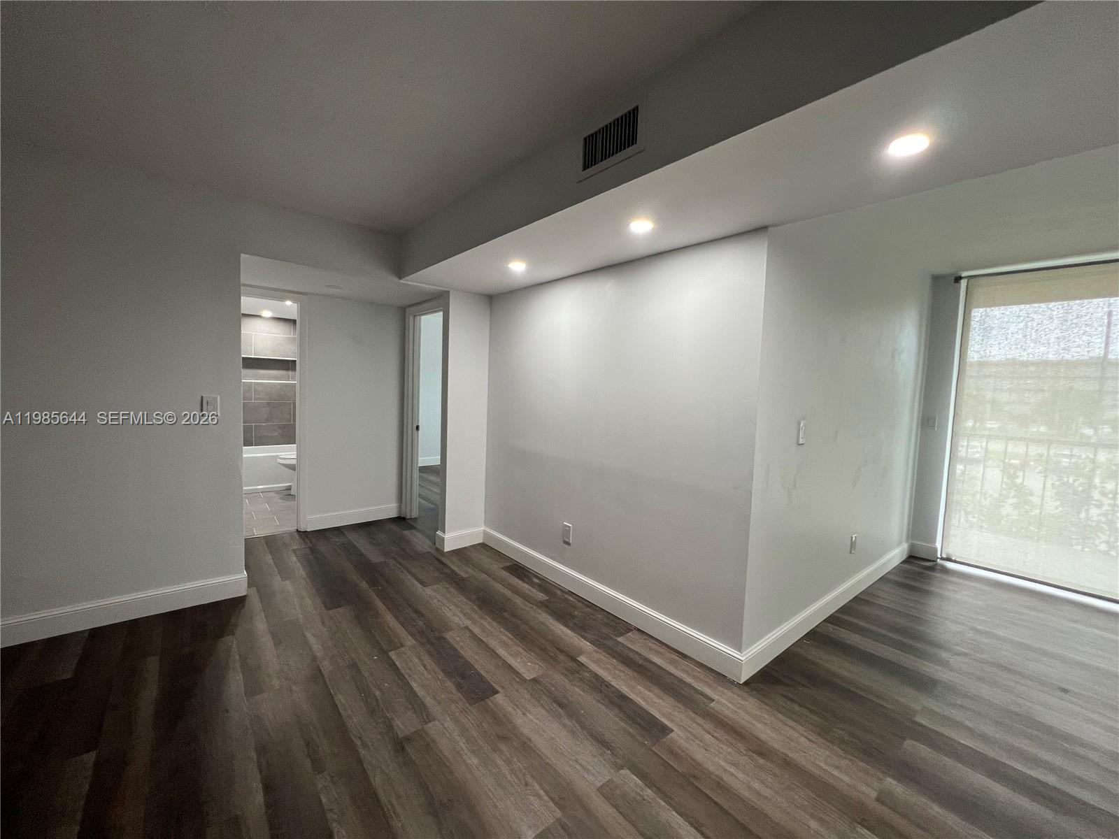 8635 Northwest 8th Street, Unit 211 Miami, FL 33126 - Photo 8 of 17 an empty room with wooden floor and windows