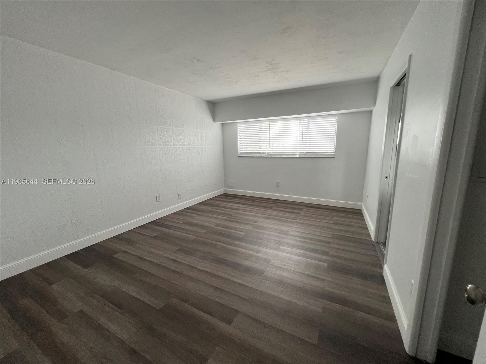8635 Northwest 8th Street, Unit 211 Miami, FL 33126 - Photo 9 of 17 a view of an empty room with wooden floor and a window