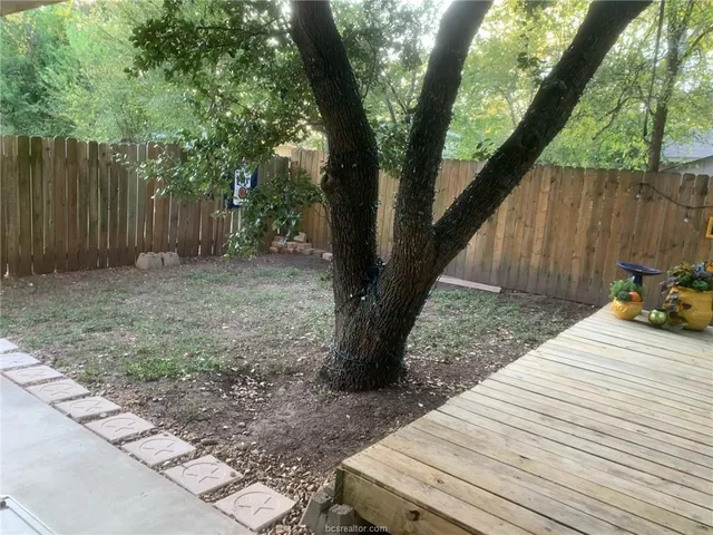 a view of a backyard with a large tree and wooden fence