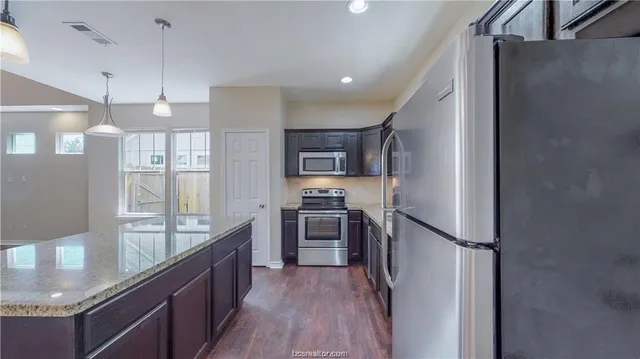 a kitchen with stainless steel appliances granite countertop a refrigerator a sink and a stove