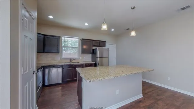 a large kitchen with stainless steel appliances a large counter top and a stove