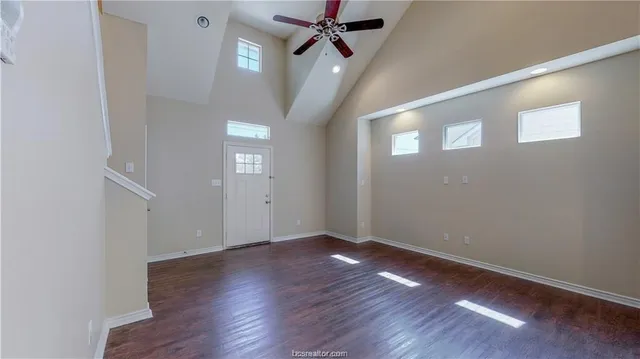 an empty room with wooden floor and hallway