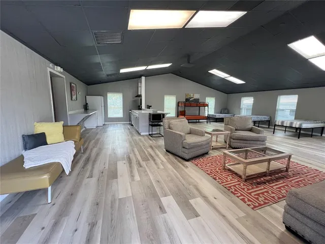 a living room with kitchen appliances and a wooden floor
