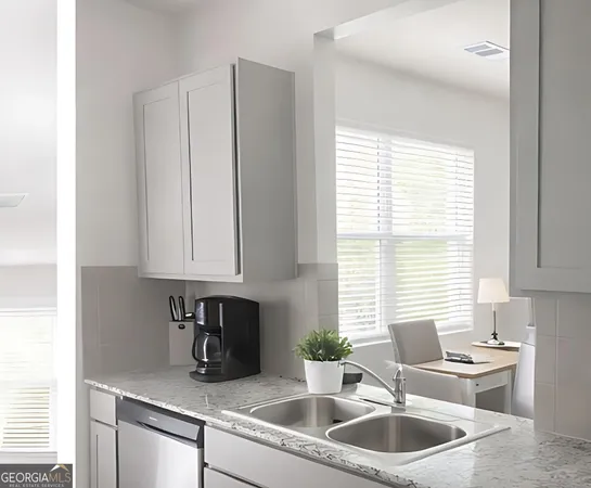 a kitchen with stainless steel appliances granite countertop white cabinets a sink and a window