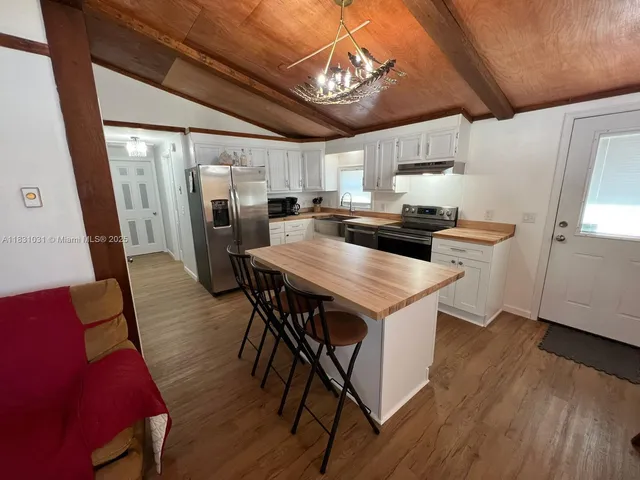 a kitchen with stainless steel appliances a dining table chairs stove refrigerator and wooden floor