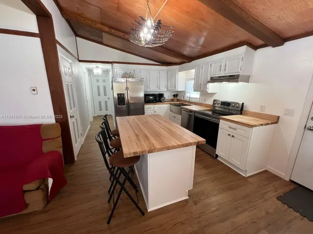 a kitchen that has a lot of cabinets a sink a stove and wooden floor