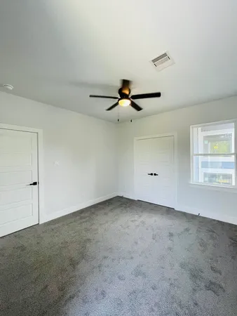 an empty room with a ceiling fan and window