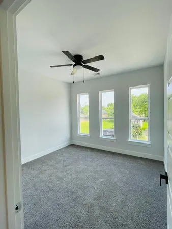 an empty room with windows and a ceiling fan
