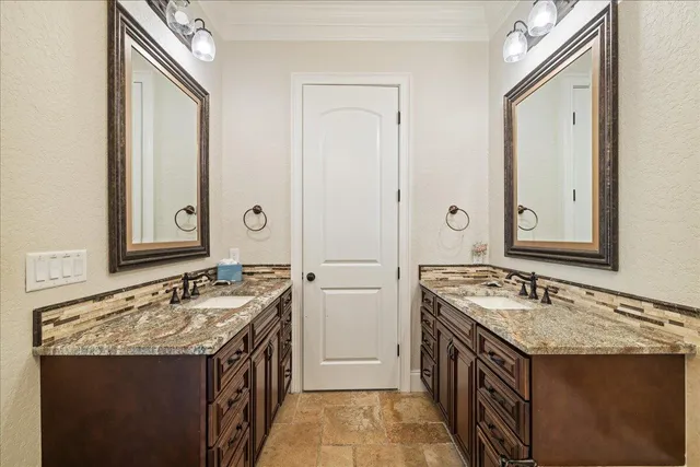 a bathroom with a granite countertop double vanity sink and a mirror