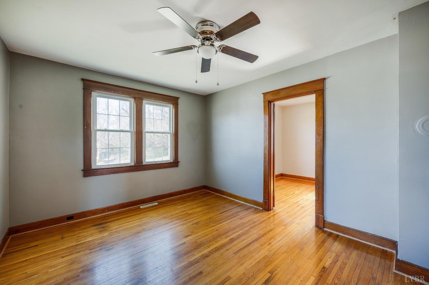 501 West Spencer Road Hurt, VA 24563 - Photo 13 of 55 an empty room with wooden floor chandelier fan and windows