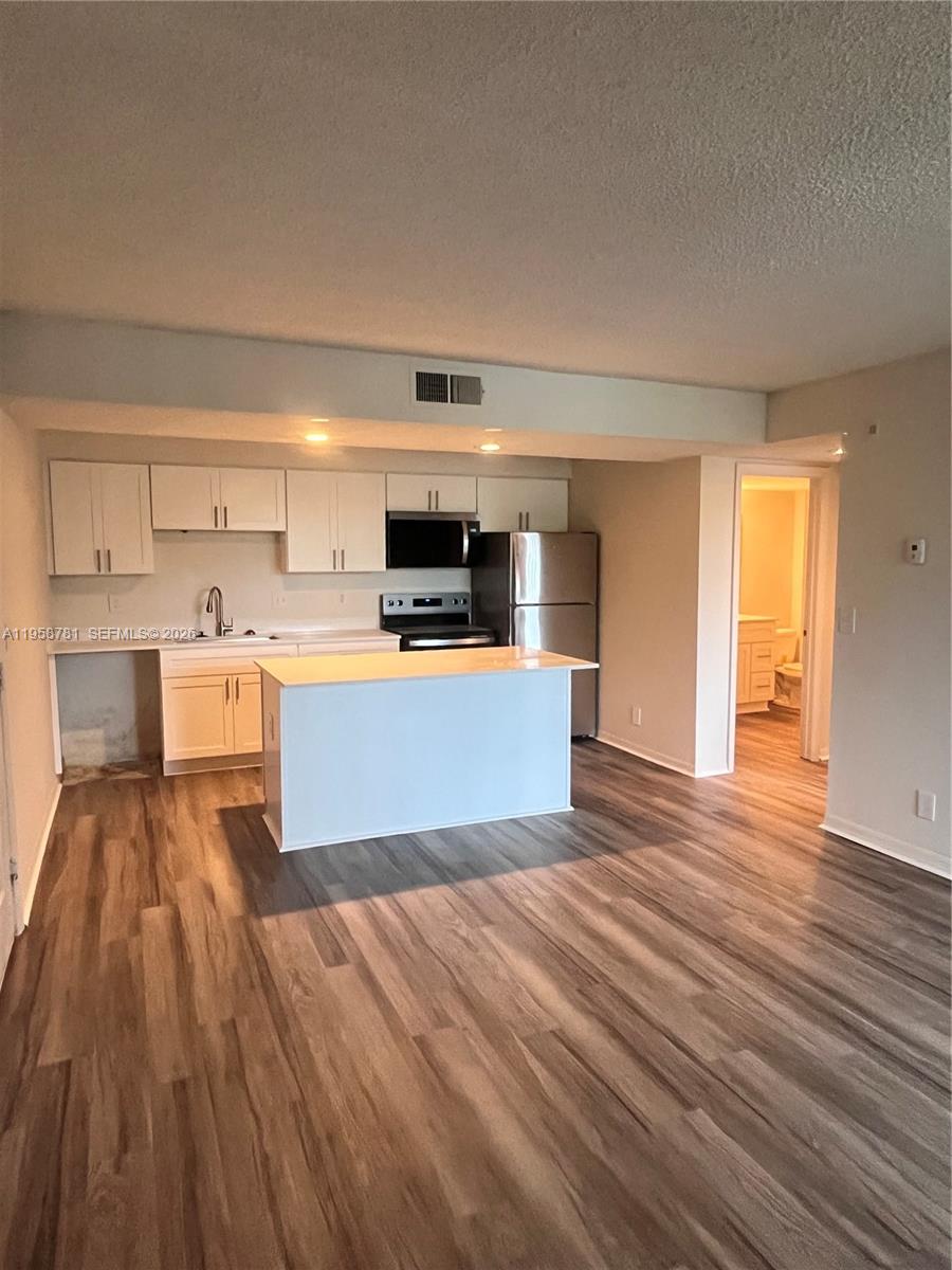 a view of kitchen with wooden floor and electronic appliances
