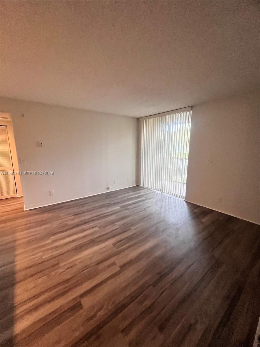 4055 West McNab Road, Unit H211 Pompano Beach, FL 33069 - Photo 3 of 22 a view of an empty room with wooden floor and a window