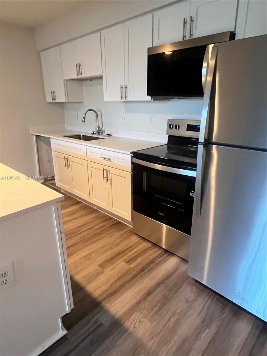 4055 West McNab Road, Unit H211 Pompano Beach, FL 33069 - Photo 4 of 22 a kitchen with stainless steel appliances a stove microwave and sink