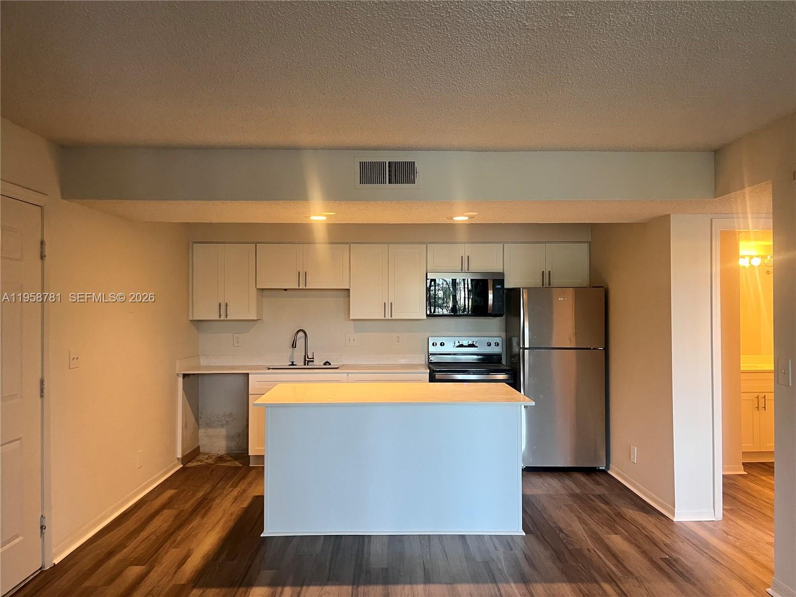 4055 West McNab Road, Unit H211 Pompano Beach, FL 33069 - Photo 6 of 22 a large kitchen with stainless steel appliances a refrigerator a stove a microwave and cabinets