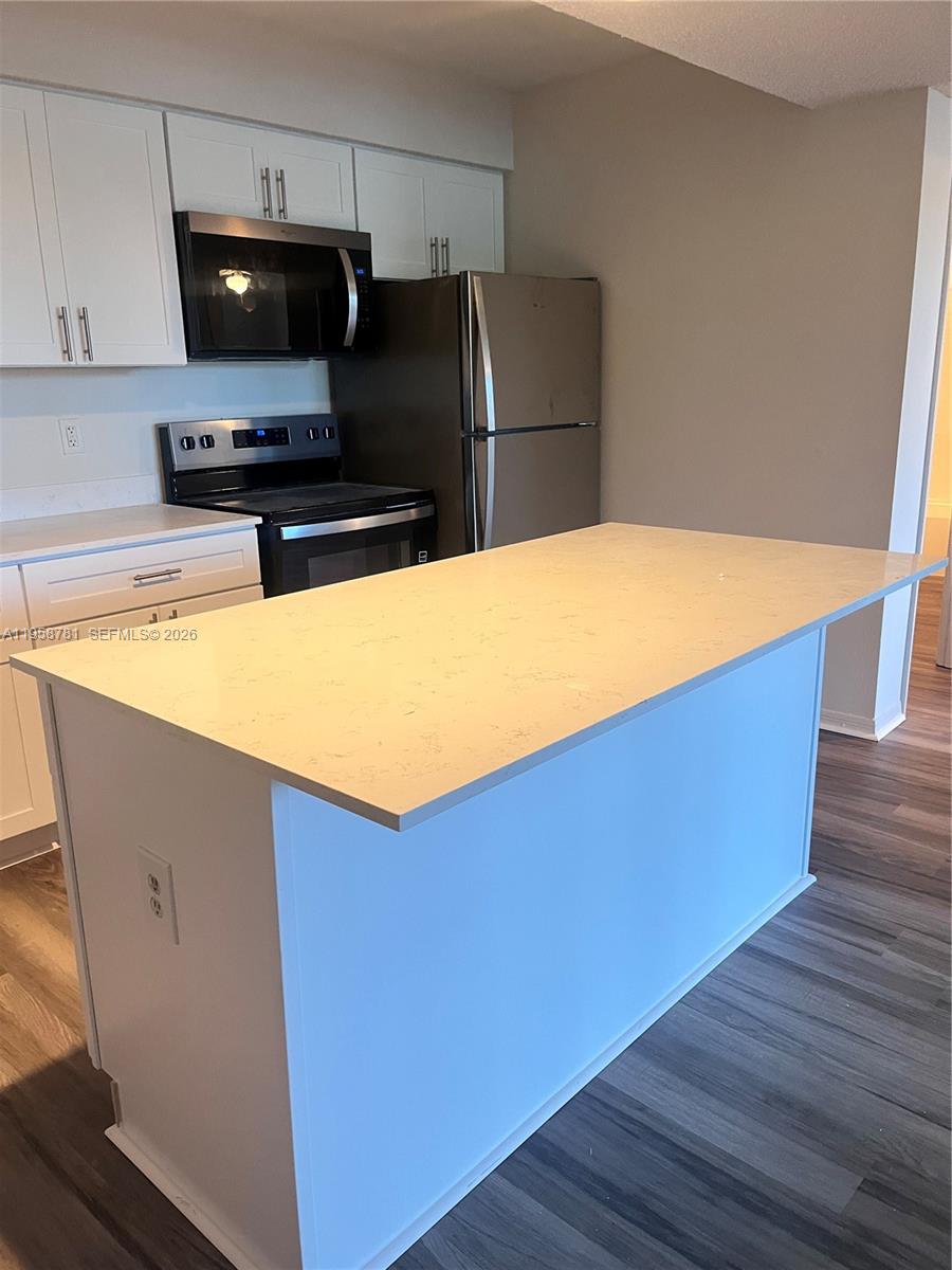 4055 West McNab Road, Unit H211 Pompano Beach, FL 33069 - Photo 8 of 22 a kitchen with stainless steel appliances a refrigerator a stove a microwave and wooden floor