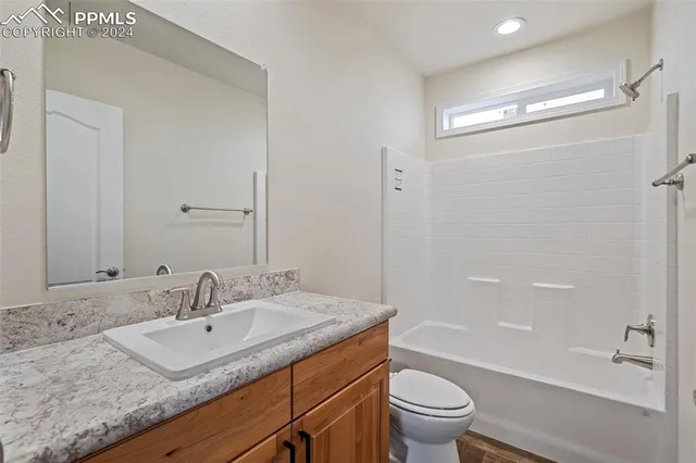 a bathroom with a granite countertop sink a toilet and shower