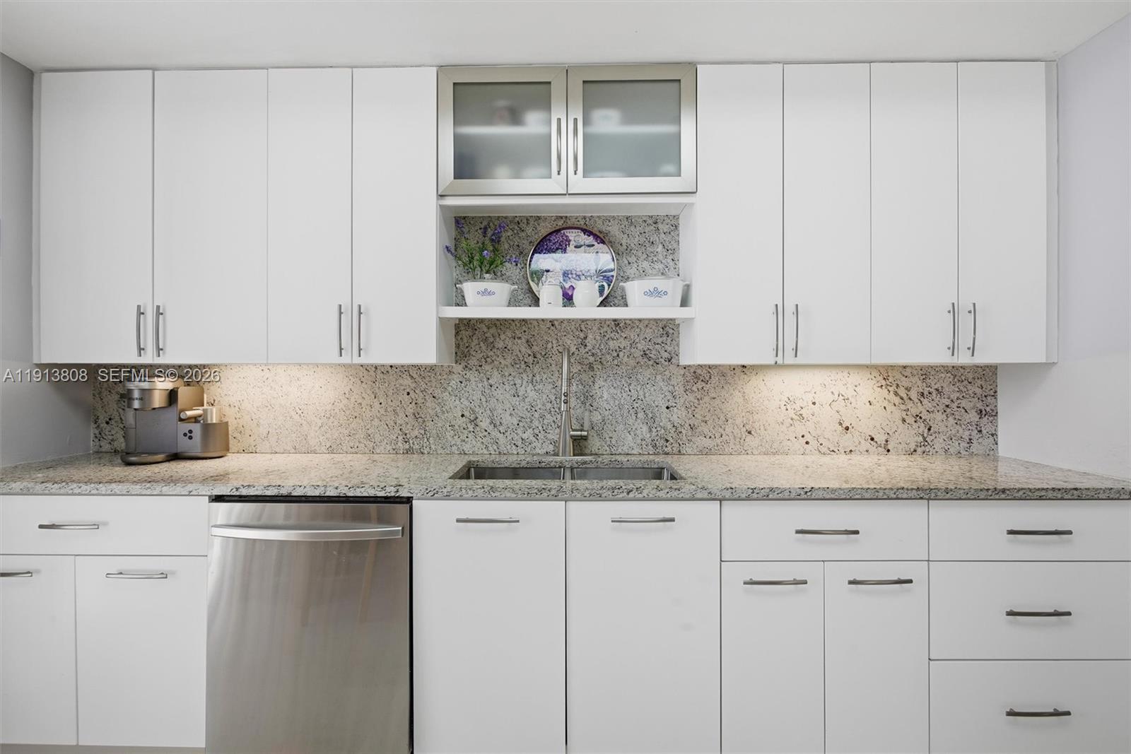 888 Brickell Key Drive, Unit 1903 Miami, FL 33131 - Photo 13 of 38 a kitchen with granite countertop white cabinets and a stove