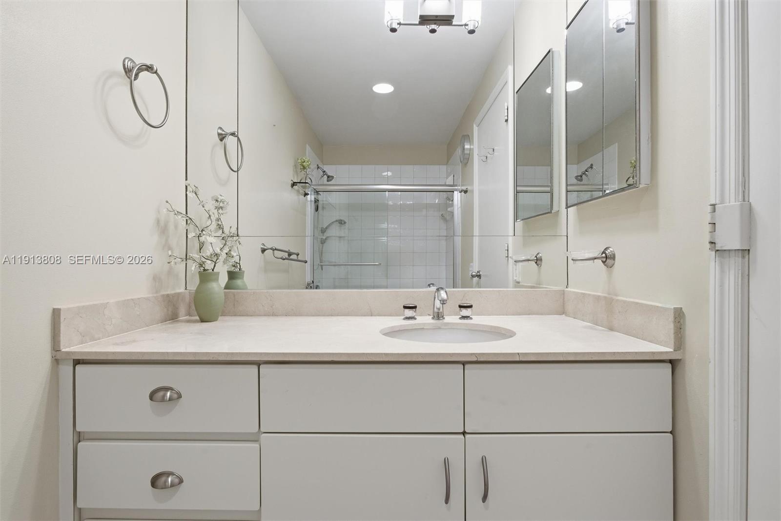 888 Brickell Key Drive, Unit 1903 Miami, FL 33131 - Photo 21 of 38 a bathroom with a granite countertop sink a mirror and shower