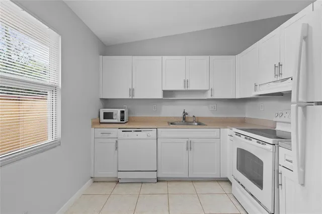a kitchen with white cabinets stainless steel appliances a sink and a window