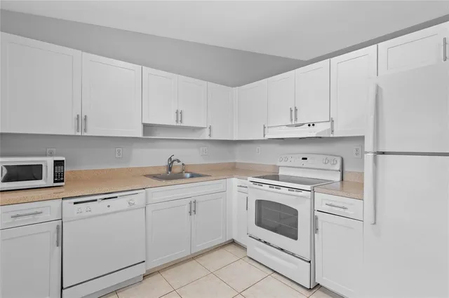 a kitchen with white cabinets and white appliances