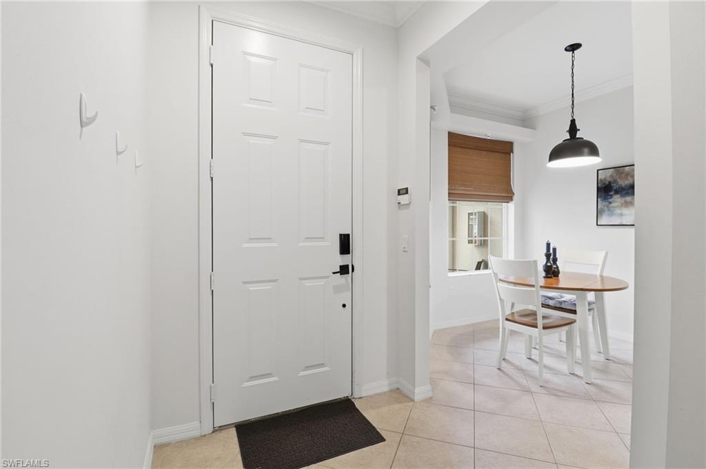 12040 Matera Lane, Unit 104 Bonita Springs, FL 34135 - Photo 14 of 36 Foyer entrance featuring crown molding and light tile patterned floors