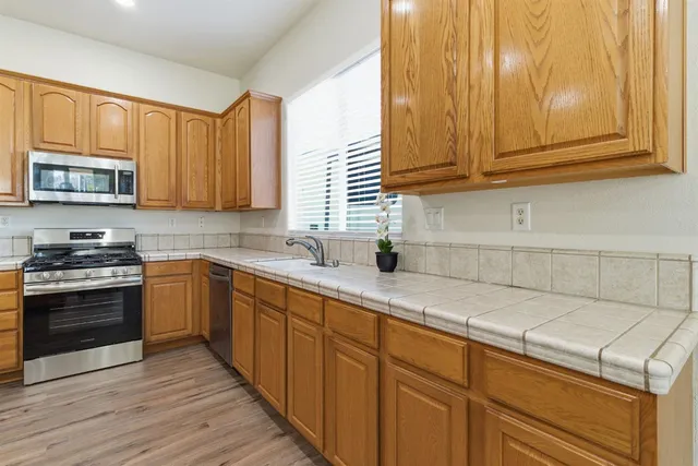 a kitchen with stainless steel appliances granite countertop wooden cabinets a stove and a sink