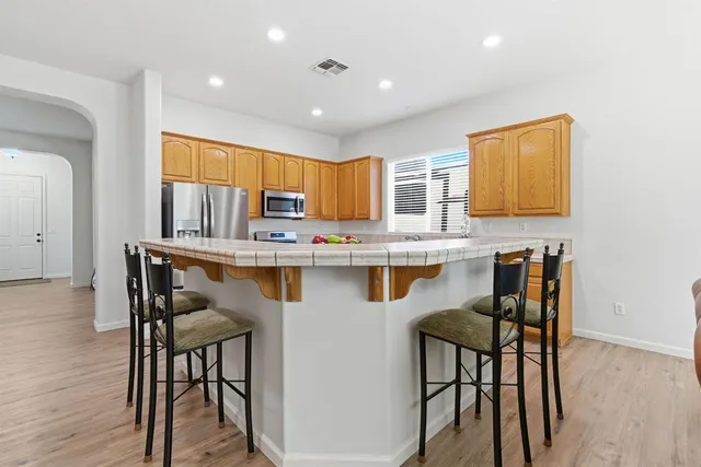 a kitchen with stainless steel appliances granite countertop a table chairs sink and cabinets