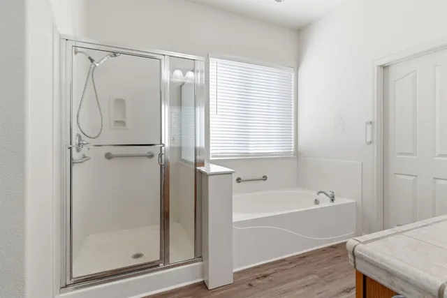 a bathroom with a bathtub a shower and a window