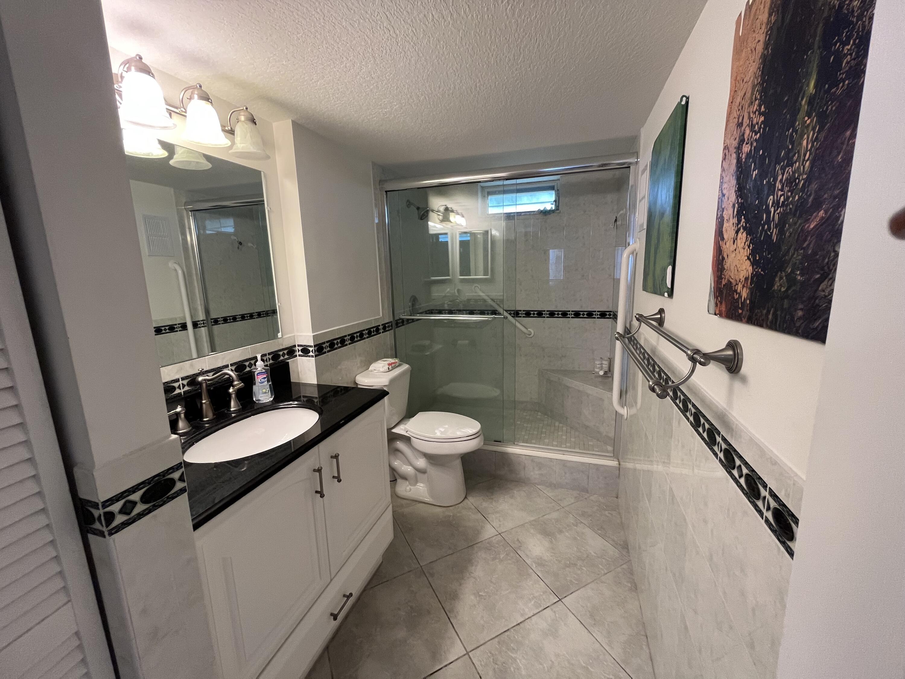 2515 Northeast 1st Court, Unit 411 Boynton Beach, FL 33435 - Photo 7 of 22 a bathroom with a double vanity sink toilet mirror and shower