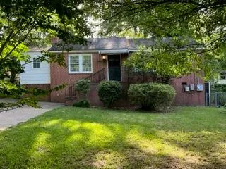 a view of a house with a yard plants and large tree