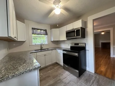 a kitchen with stainless steel appliances granite countertop a sink stove and microwave